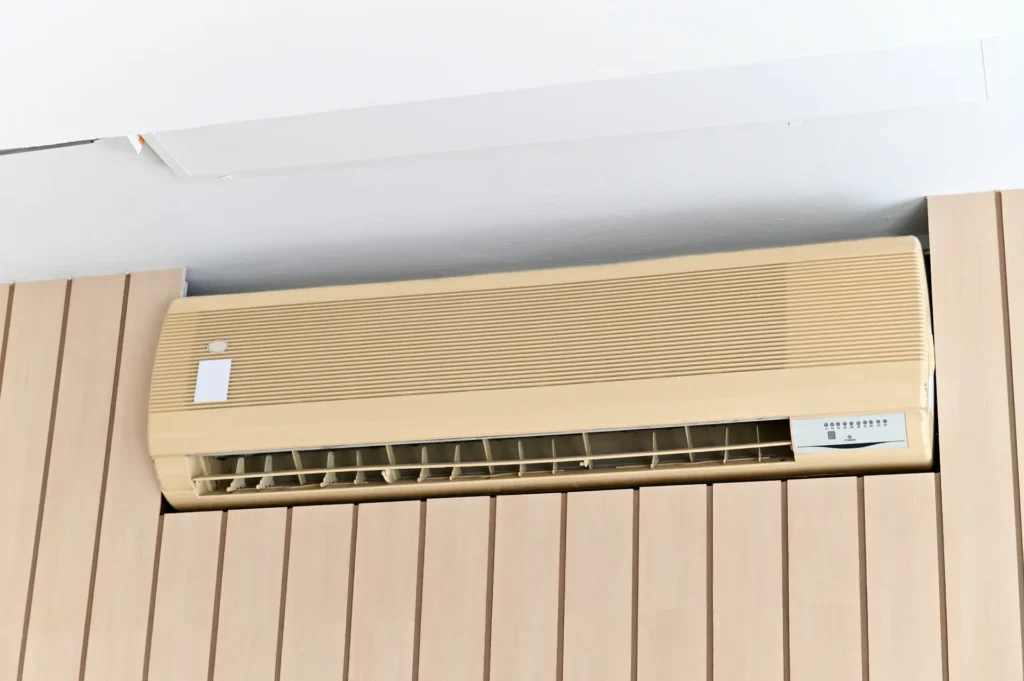 Old wall mounted air conditioner installed on a brown wooden wall