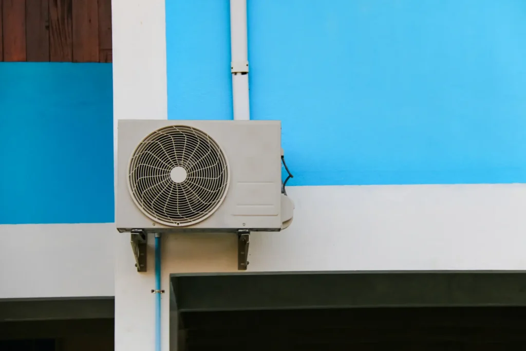 Outdoor AC unit mounted on a blue wall