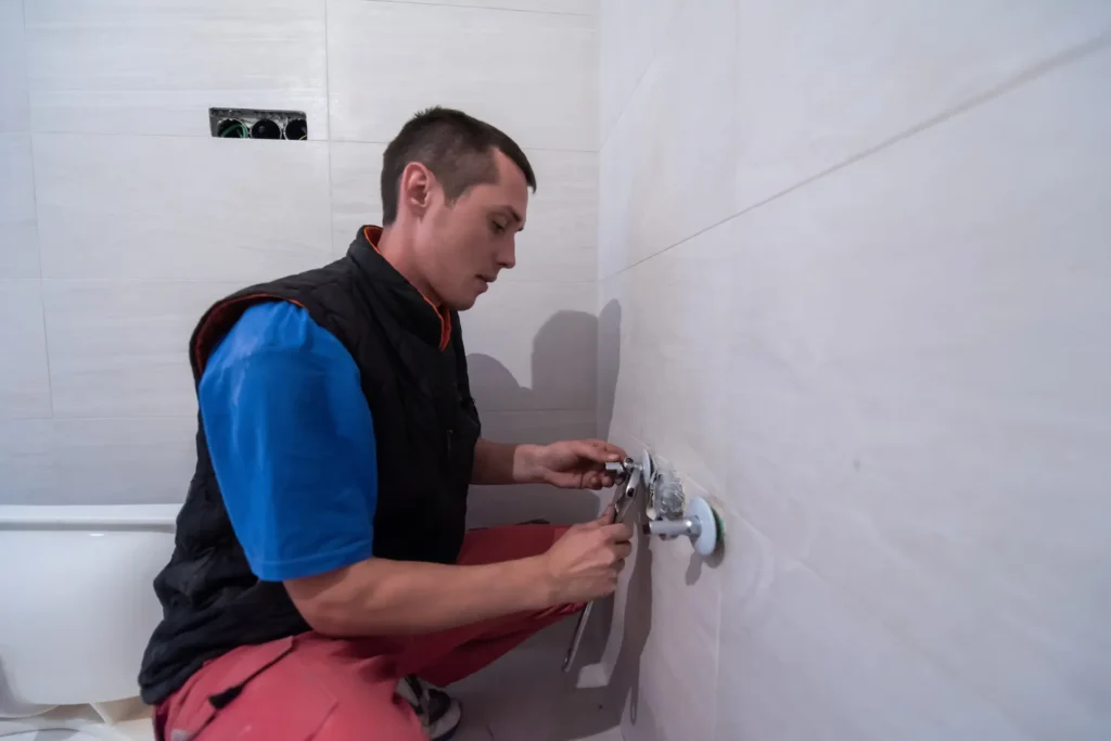 Plumber fixing a bathroom water pipe fitting