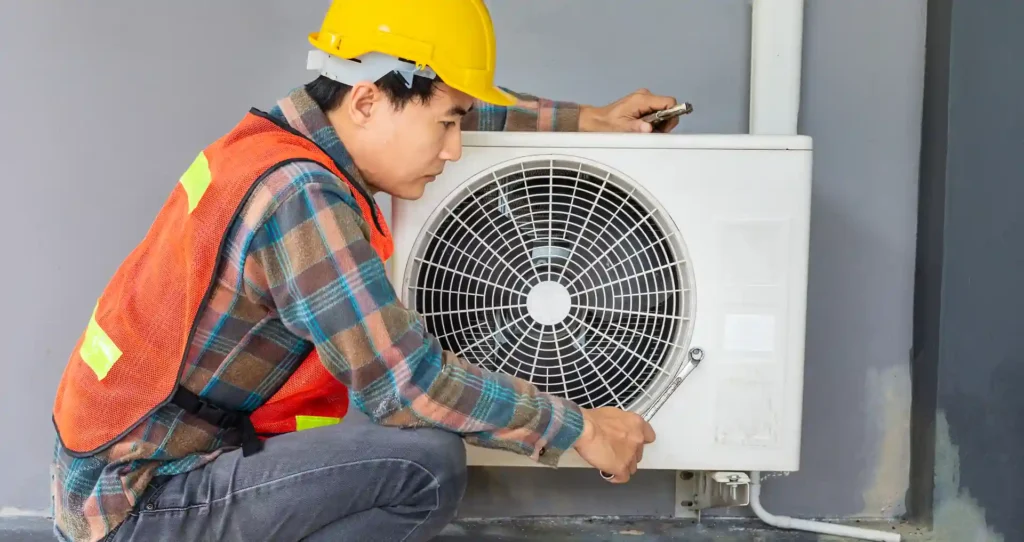 Technician repairing an outdoor air conditioning unit with a wrench.